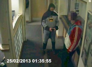A man dressed as Batman and a burglary suspect stand in a police station in Bradford, northern England